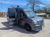 Dark gray Mercedes-Benz Sprinter van, an RV rental, with doors open in a sunny parking lot. Ready for adventure.