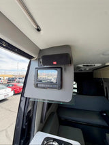 RV rental's smart interior: control panel, JBL speaker, ambient lighting, and grey seating, looking out to a bright parking lot.
