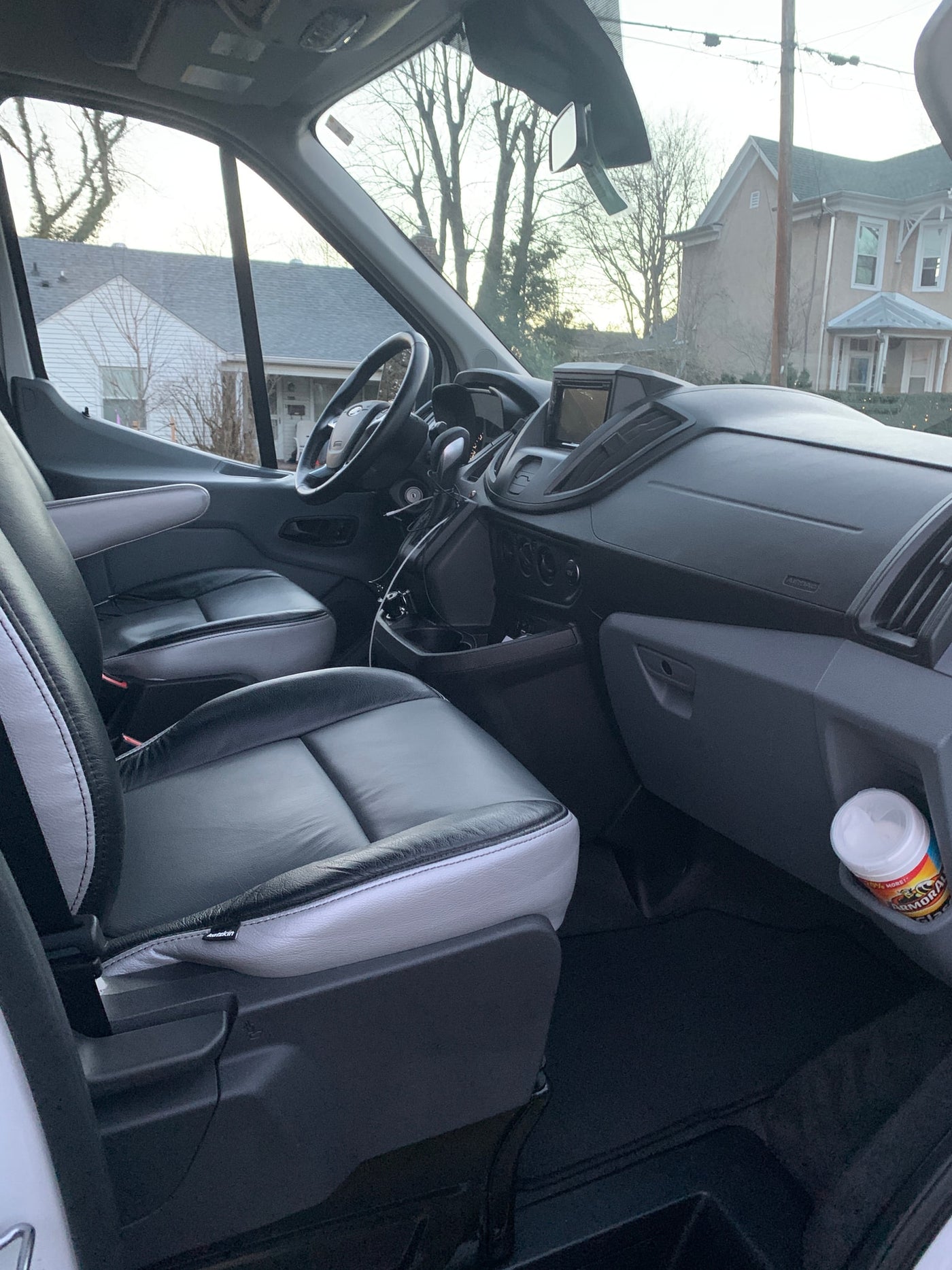 RV rental van interior: black/grey leather seats, modern dashboard, and bright window views of a neighborhood. — photo 15