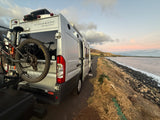 Winnebago RV rental parked seaside at sunset with bike mount, ready for scenic ocean road trips and adventure!