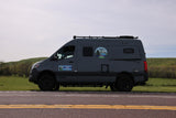 Gray Winnebago Revel 4x4 RV rental van on a road. Ready for smart adventures amidst green hills.
