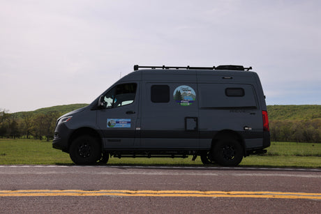 Gray Winnebago Revel 4x4 RV rental van on a road. Ready for smart adventures amidst green hills.