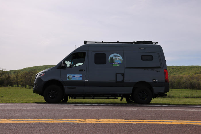 Gray Winnebago Revel 4x4 RV rental van on a road. Ready for smart adventures amidst green hills.