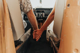 Adventure-bound rv rental: Couple's hands intertwined in their cozy vintage camper, ready for travel.