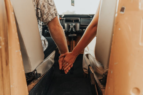 Adventure-bound rv rental: Couple's hands intertwined in their cozy vintage camper, ready for travel.
