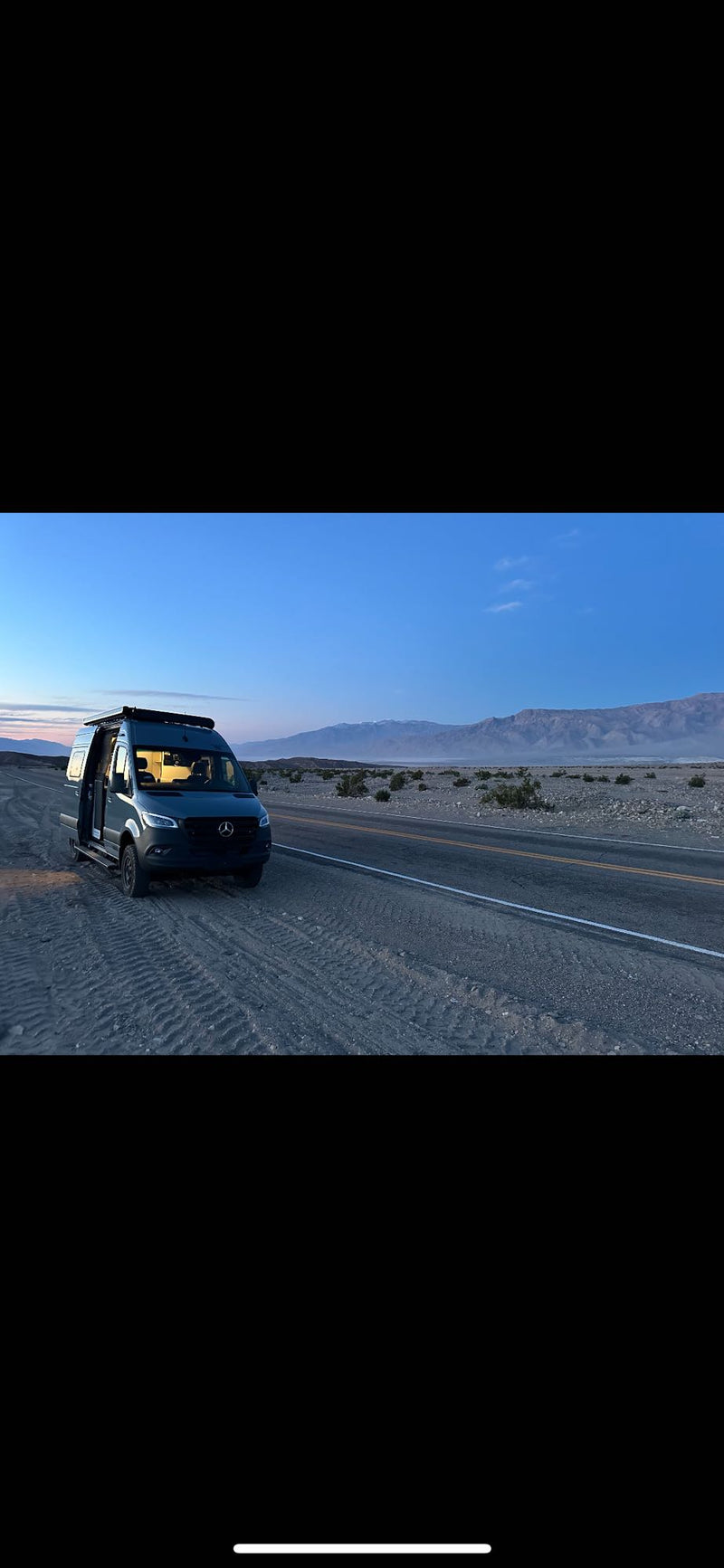  and kayak in a scenic desert.|Woman smiles from her grey RV rental|Adventure-ready Winnebago Revel 4x4 RV rental parked in scenic red rock mountains under a clear sky.|A modern grey RV rental with off-road tires — photo 7