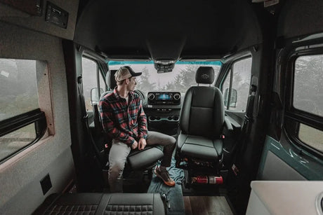 Man in an RV rental camper van, looking out at the rainy view. Ideal for cozy travels.