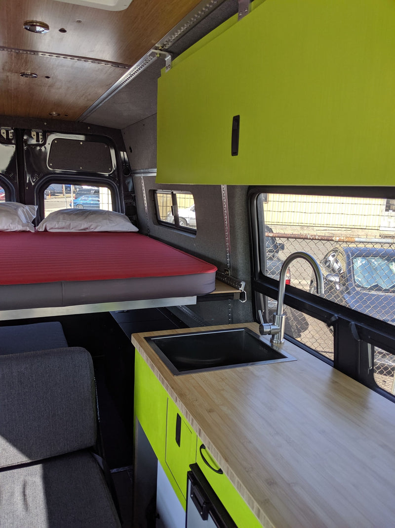 Rv rental van interior: lime green cabinets, kitchen with sink, bed, and grey seating area. A well-equipped camper van. — photo 6