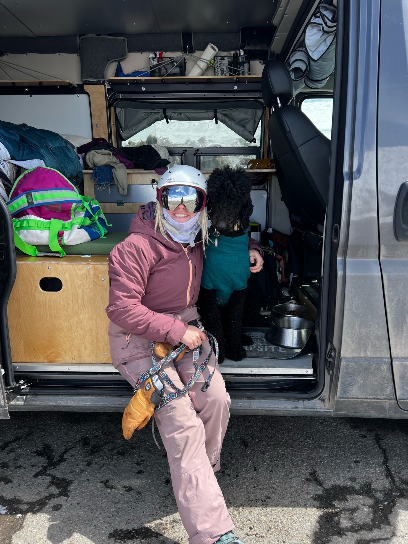 A person in ski gear and their dog relax inside an **rv rental** camper van, highlighting a perfect dog-friendly ski trip.