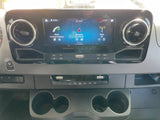 RV rental dashboard: touchscreen infotainment showing navigation, phone, radio; plus climate controls and cup holders.