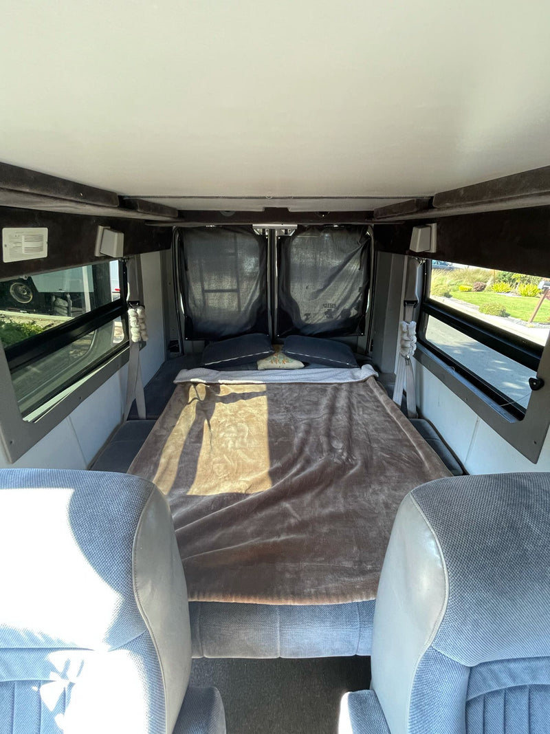  surrounded by scenic hills. Ideal for travel adventures.|Side view of a modern white camper van with large dark windows and a raised pop-top roof — photo 4