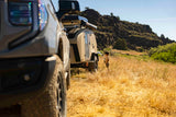 Enjoy your RV rental adventure! A child by an Escapapod camper trailer & truck in a sunny, arid landscape.