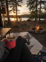 From a first-person perspective at our RV rental campsite, holding coffee, watching a lakeside sunset & campfire.