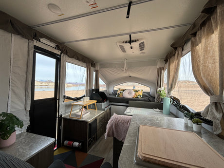 Interior of a comfortable rv rental pop-up camper with kitchen, bed, and stunning lake views. Ideal for camping.