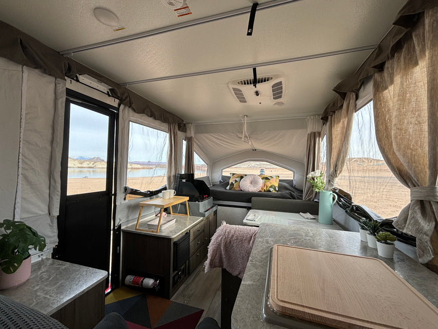 Interior of a comfortable rv rental pop-up camper with kitchen, bed, and stunning lake views. Ideal for camping.