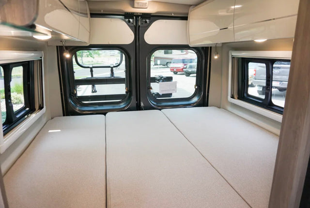  and large rear windows for comfort and views.|RV rental camper van interior. Spacious sleeping area with three mattress sections