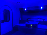 Cozy blue-lit RV rental interior featuring a door, comfortable seating, and a modern charging station.