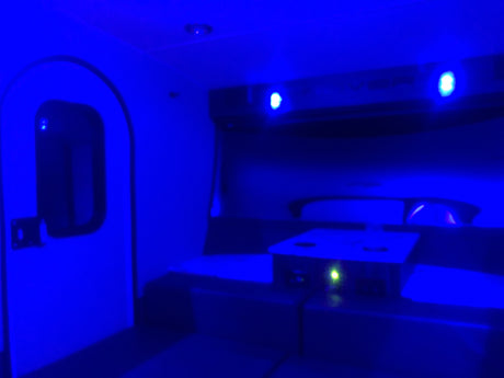 Cozy blue-lit RV rental interior featuring a door, comfortable seating, and a modern charging station.