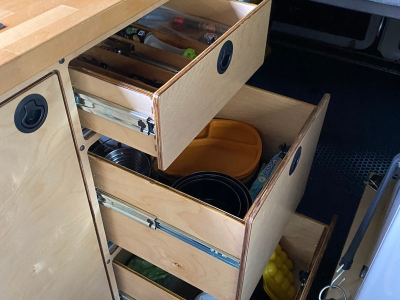 Organized plywood drawers in an RV rental, with kitchen items like plates and pots, showing efficient storage for travel. — photo 18