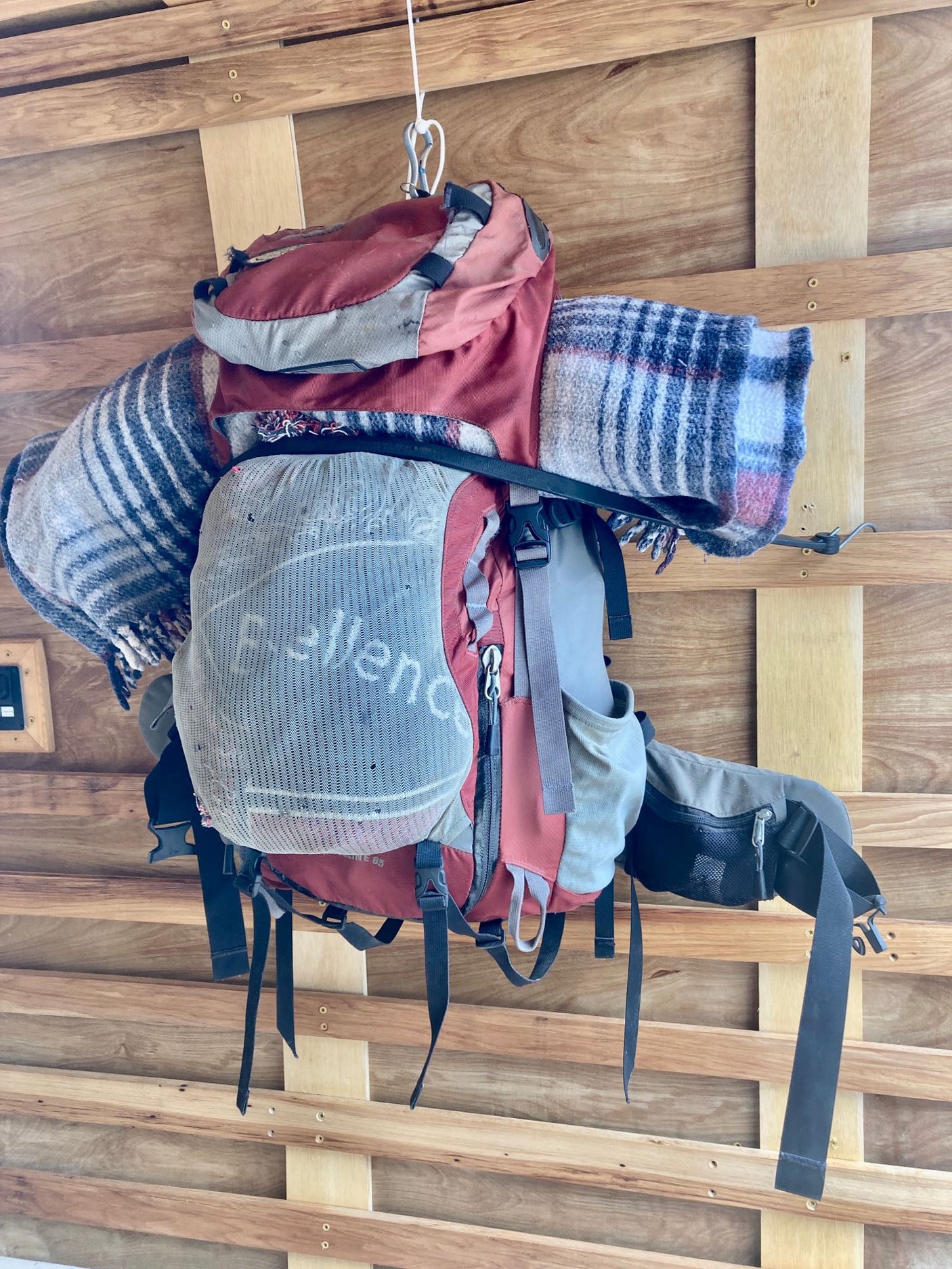 Traveler's backpack & blankets hung on wooden RV rental walls. Smart storage for your next adventure trip.