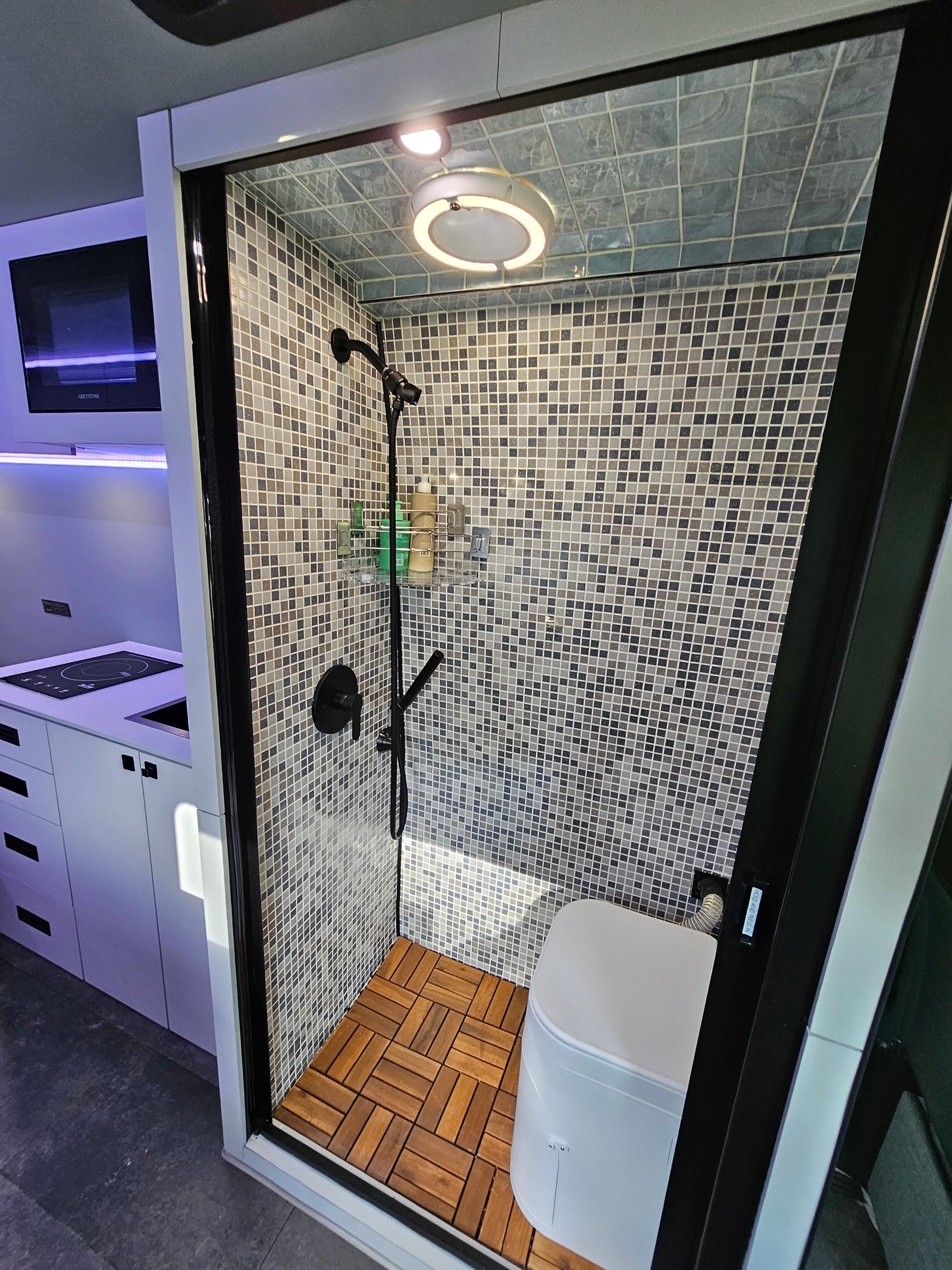Modern RV rental interior with compact shower/toilet and kitchen area, perfect for travel.