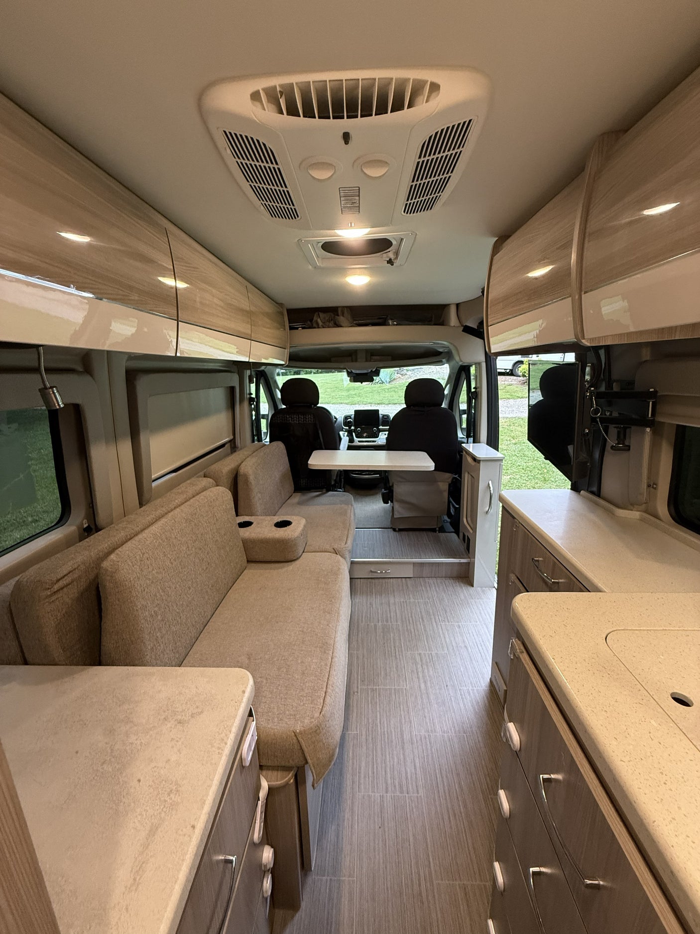 Explore this modern rv rental interior, featuring a lounge with cup holders, dining table, kitchen, and ample storage.
