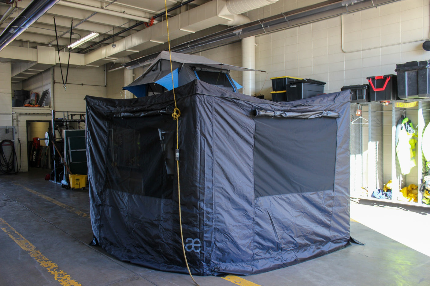 RV rental display: A black overlanding vehicle awning and rooftop tent set up indoors, ideal camping gear.