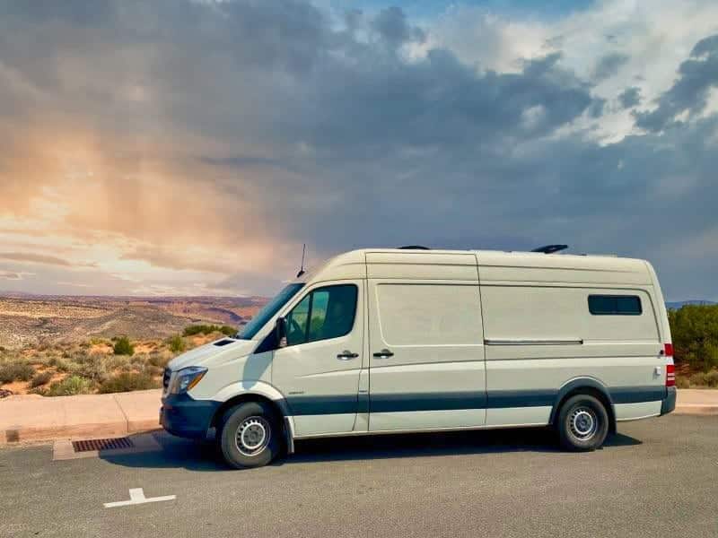 White camper van RV rental parked with a desert landscape and cloudy sky with sun rays in the background. Perfect for a road trip! — photo 1