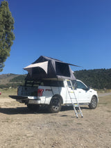 A white Ford F-150 pickup with rooftop tent setup, a great 'RV rental' alternative for rugged outdoor camping.