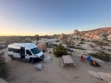 RV rental adventure: Desert camping with a camper van, campfire, and stunning rock formations.