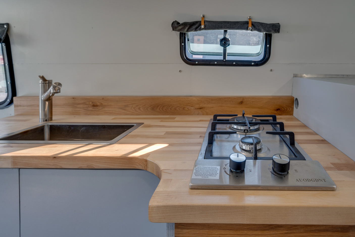 Modern RV rental kitchen with compact sink and two-burner stove. Perfect for on-the-road cooking.