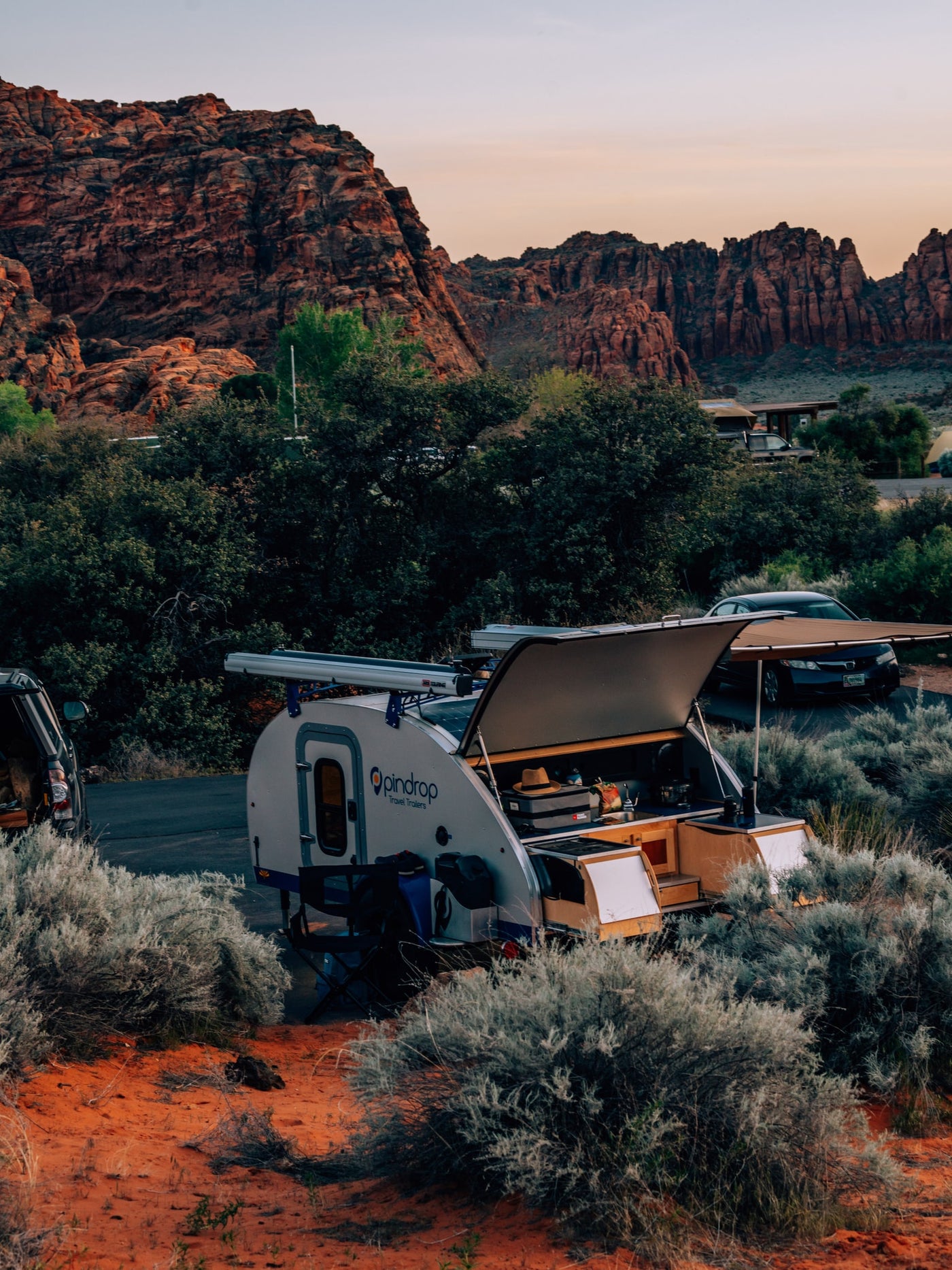An Opindrop teardrop rv rental is set up in a red rock desert campsite with an open kitchen, perfect for nature travel. — photo 5