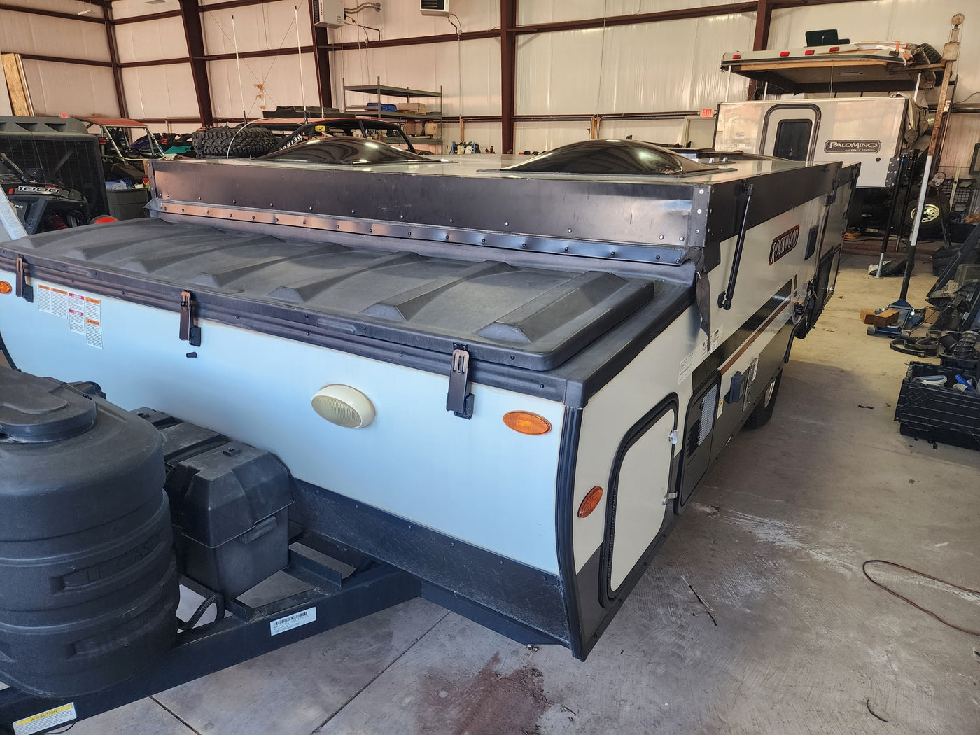 Closed Rockwood pop-up camper, ready for rv rental, stored in a large industrial garage setting with other vehicles. — photo 12