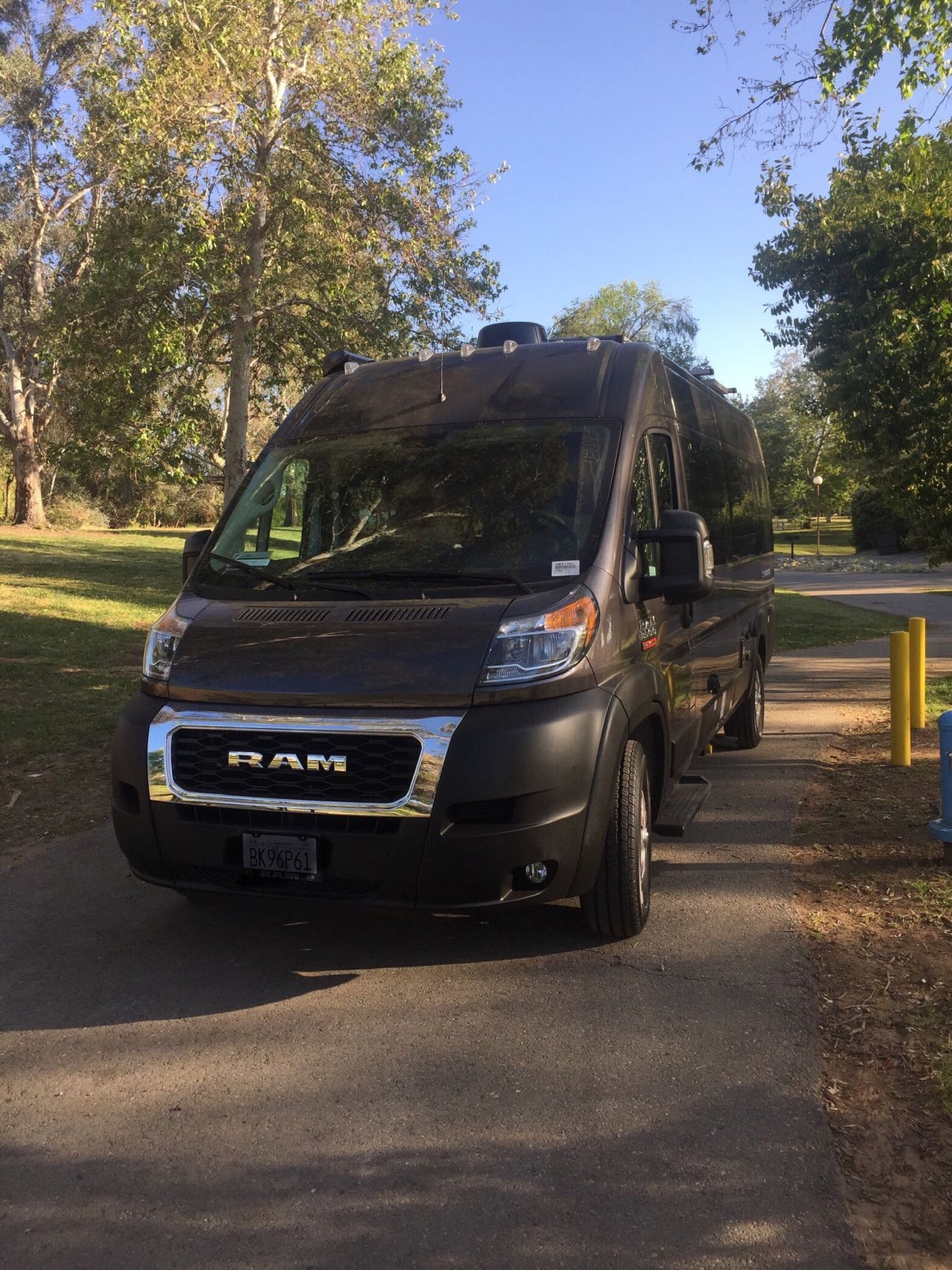  surrounded by lush trees and grass.|Dark RAM ProMaster RV rental van — photo 2