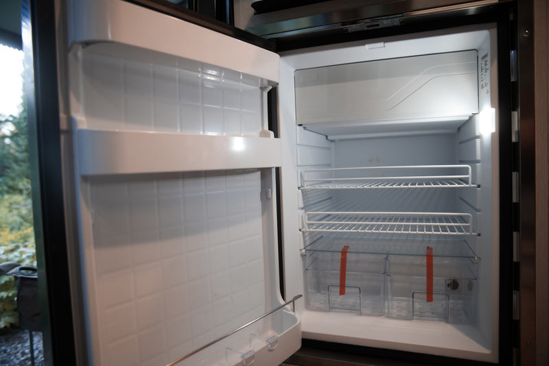 Empty, clean RV rental refrigerator interior, ready for your travel essentials, featuring wire shelves and crisper bins. — photo 9