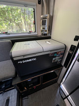 Compact RV rental interior featuring a Dometic cooler, heater, and scenic window view. Perfect for travels.