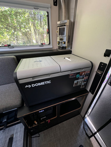 Compact RV rental interior featuring a Dometic cooler, heater, and scenic window view. Perfect for travels.