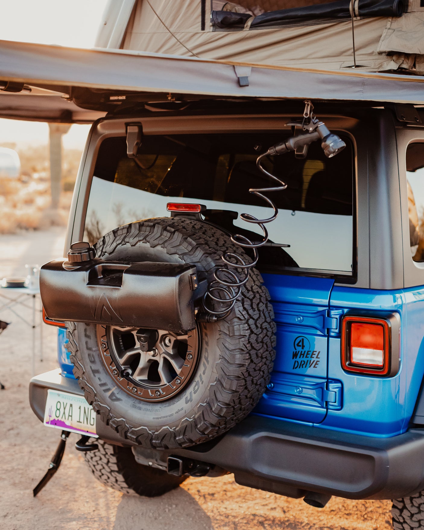 This blue RV rental Jeep Wrangler, with a rooftop tent and outdoor shower, is ready for overlanding adventures.