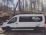 White Van Life KC RV rental van in a bare-treed forest with rocky ground. Perfect for your next adventure.