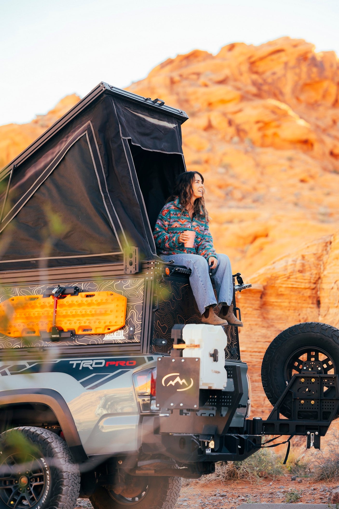 Woman enjoying desert views from her truck's pop-up camper, perfect for an overlanding rv rental adventure.