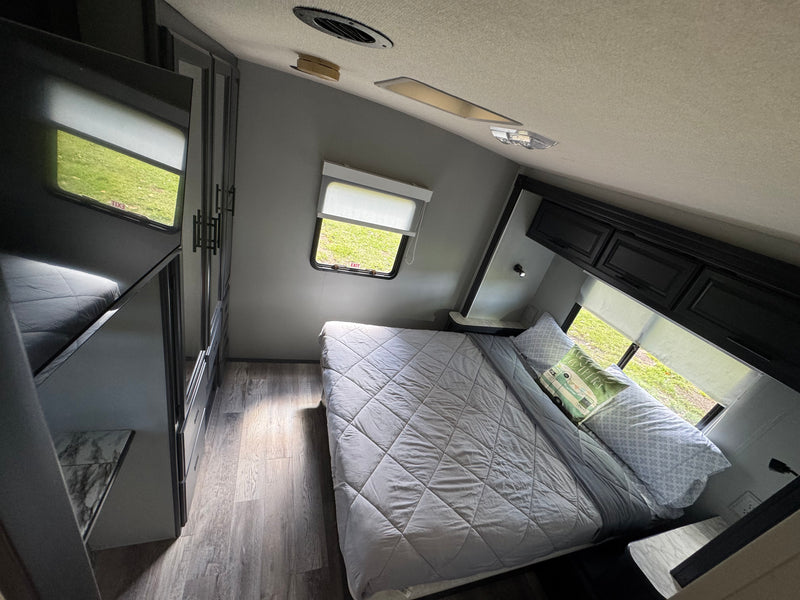 Cozy RV rental bedroom featuring a comfortable bed, built-in storage, and scenic views. Perfect for travel accommodation. — photo 11