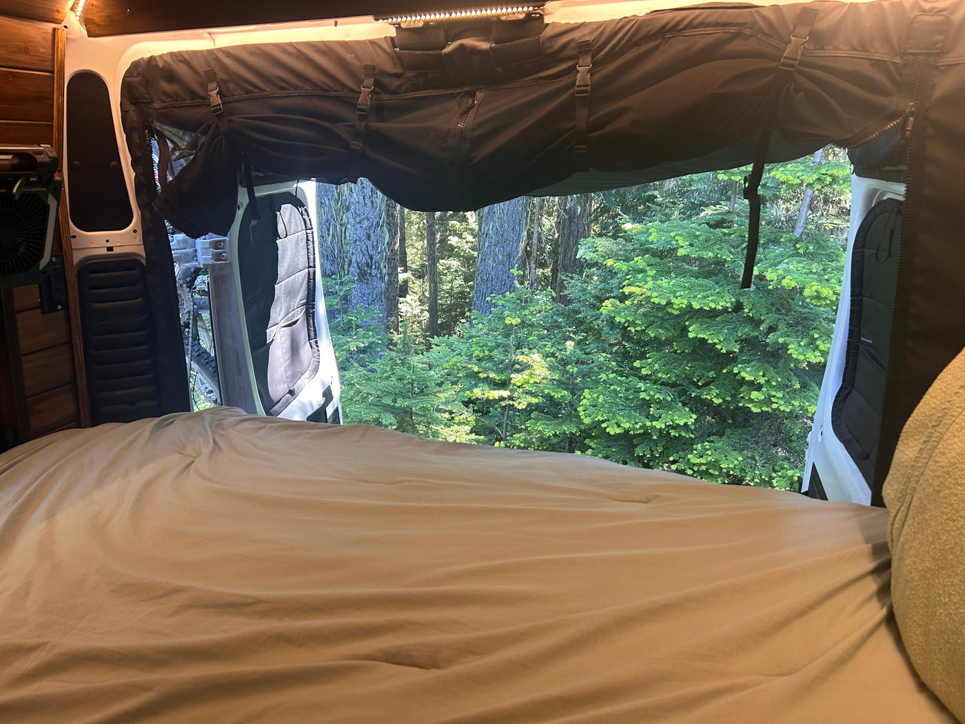 Wake up to nature! This cozy rv rental features a comfy bed and open back doors revealing a vibrant forest view. — photo 13