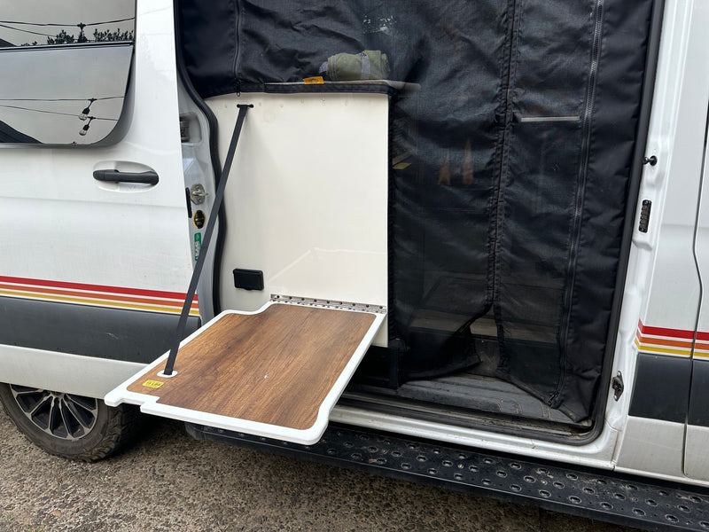  celebrating amidst striking rock formations.|A dirty white rv rental camper van with adventure gear parked lakeside before snowy mountains under a cloudy sky.|This RV rental features a convenient side door with a fold-down — photo 18
