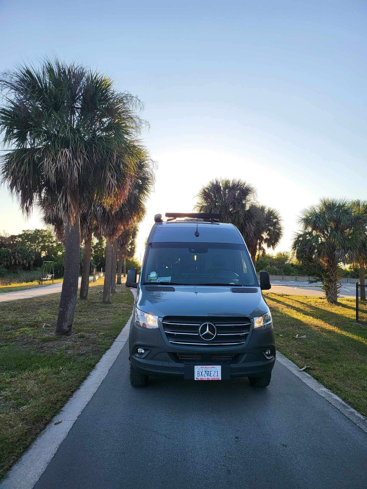A sleek dark grey Mercedes Sprinter RV rental parked on a sunny road lined with palm trees. Perfect for adventure! — photo 5