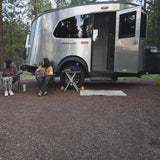 Two people lounge by their Airstream RV rental, embracing outdoor travel. A perfect setup for a relaxing camping trip.
