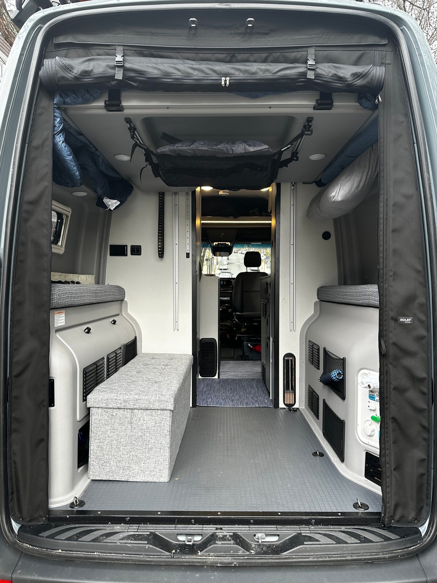 Interior of an RV rental: A well-appointed camper van with flexible seating, overhead storage, and textured gray flooring. — photo 7