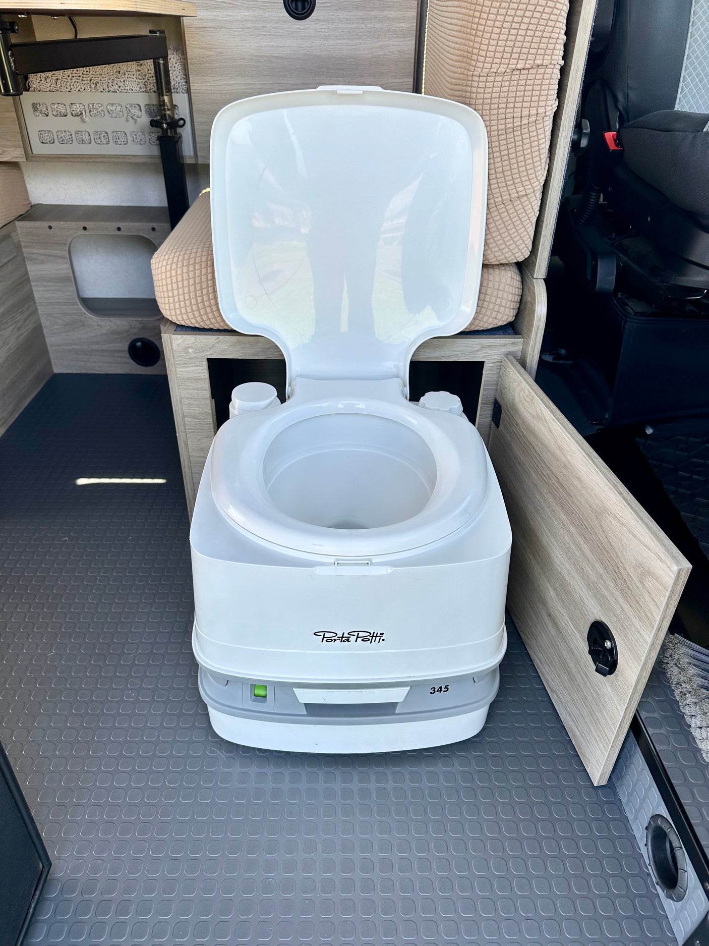 This rv rental shows a clean portable toilet (Porta Potti 345) inside a camper van, ideal for travel.