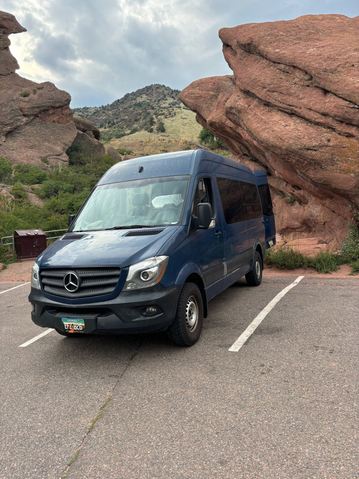 Blue Mercedes Sprinter RV rental van parked among Colorado's red rock formations and mountains. Ideal for scenic travel.|This dark blue Mercedes-Benz Sprinter van