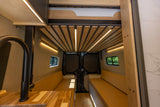 Inside a custom **camper van**: illuminated wooden ceiling, cozy benches, and kitchen. Perfect for your **RV rental** trip.