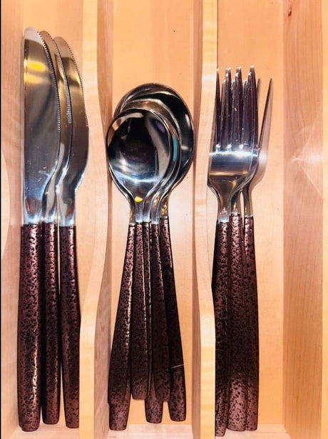 Shiny cutlery set with unique textured handles in a wooden organizer, ideal for an RV rental kitchen.